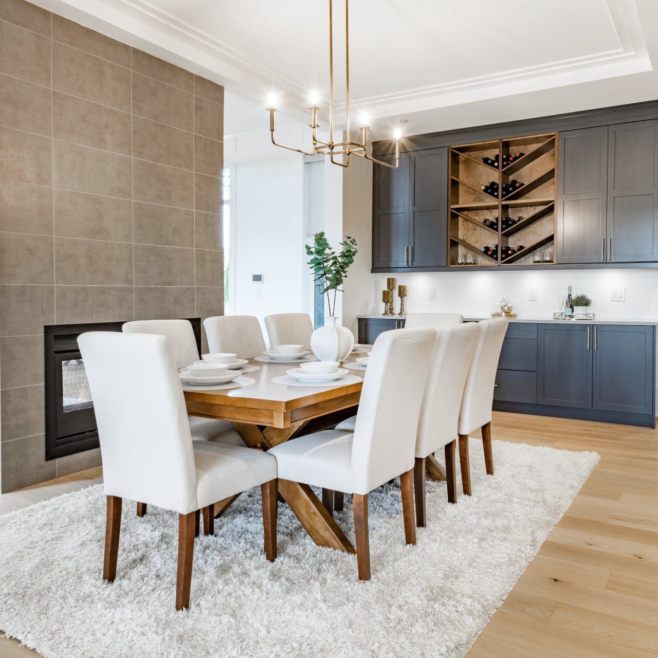 Dining room with a set table, tiled fireplace wall, and built-in wine display.