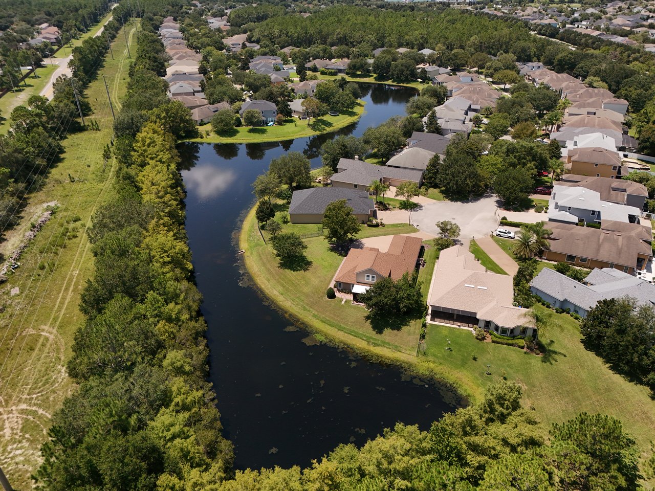 Aerial view of homes around a tree-lined pond in Austin Park, Nocatee.