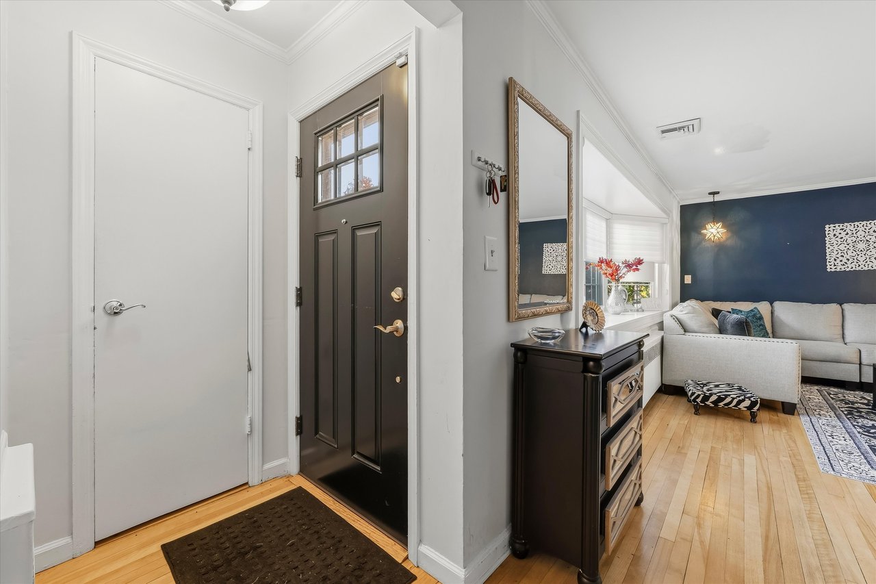 Entry foyer with a black front door and hardwood floors opening to a living room with a navy accent wall.