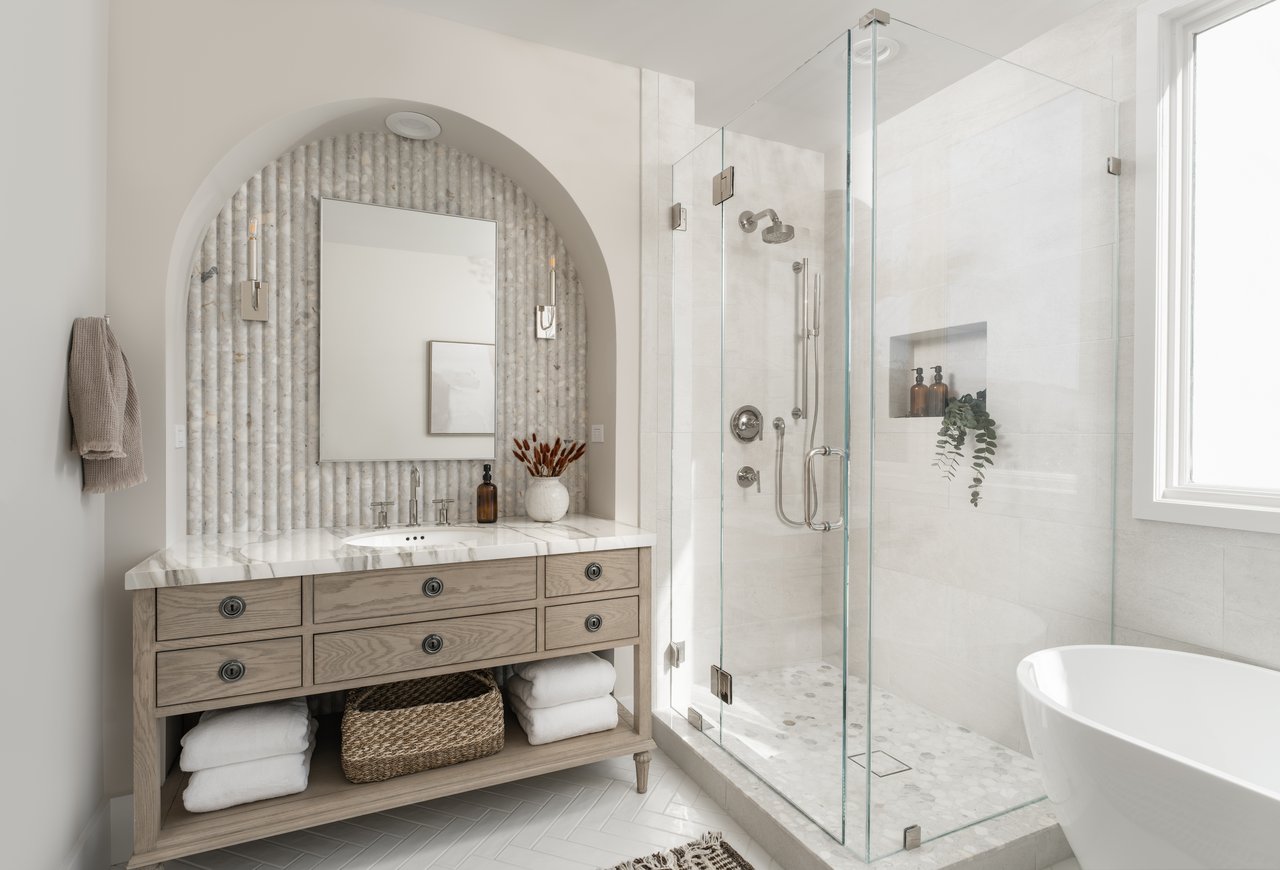 Bathroom with an arched vanity alcove, glass walk-in shower, and freestanding tub.