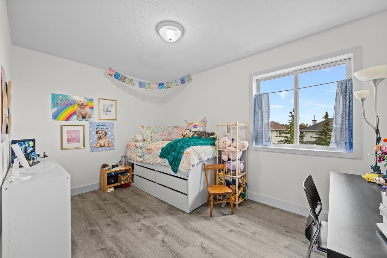 Bedroom with colorful bedding, puppy-themed wall art, and a large curtained window.