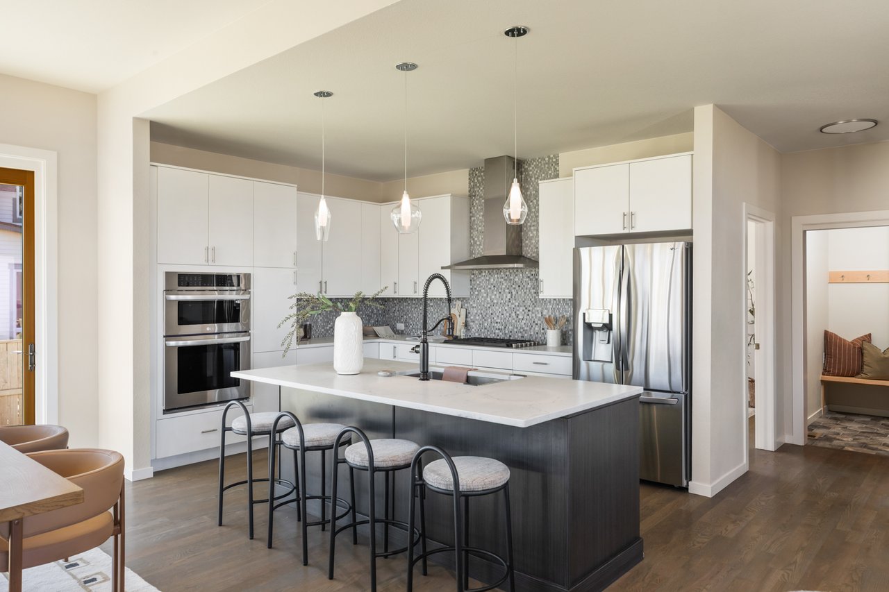 Angled kitchen view with island seating, a stainless refrigerator, and a doorway to the office