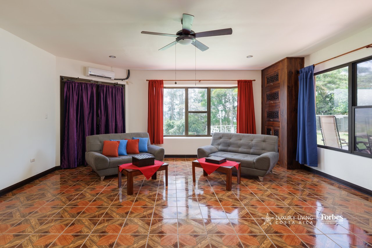 Living room with two gray sofas, colorful curtains, and glossy patterned tile floors.