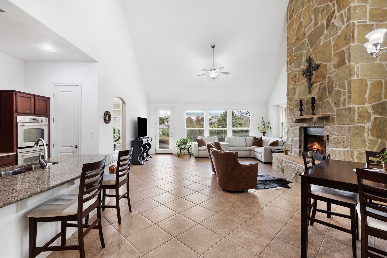 Open-plan living room with a floor-to-ceiling stone fireplace and vaulted ceiling.