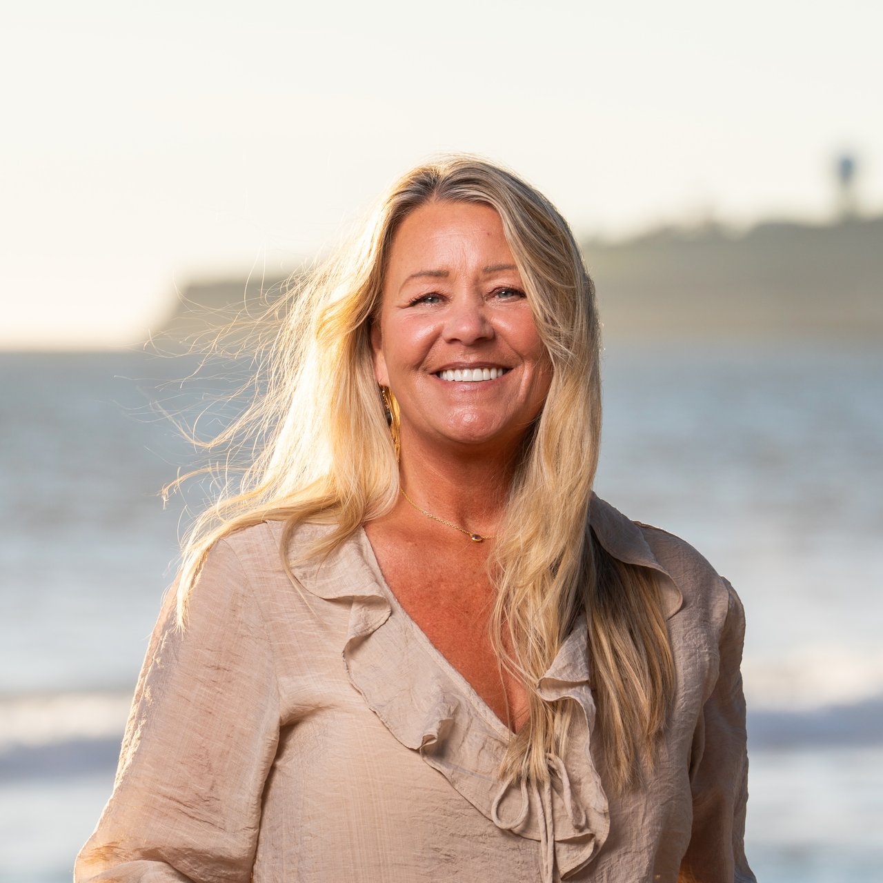 Stephanie Duncan, listing coordinator at Ocean Element Real Estate, standing on a beach in Half Moon Bay along the San Mateo County Coastside