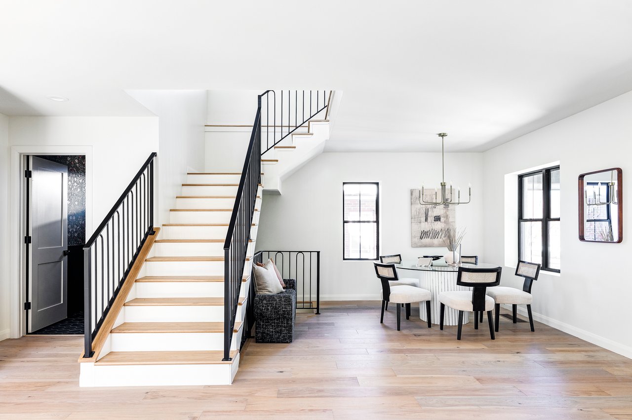 Stairwell leading upstairs with entry to lower-level bathroom on the left and dining room table on the right