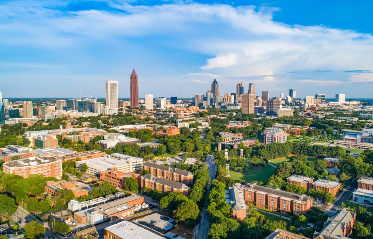 Aerial view of a city skyline beyond tree-lined neighborhoods.