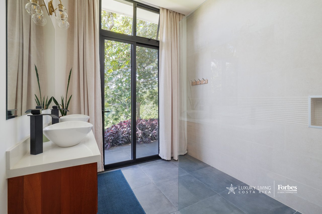 Modern bathroom with a vessel sink, wood vanity, and tall garden-facing window.