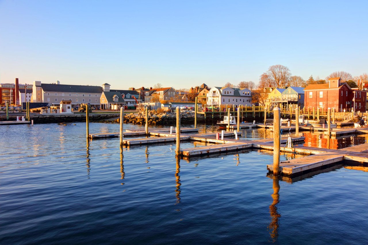 Waterfront town and marina with empty docks and colorful shorefront buildings in warm evening light.