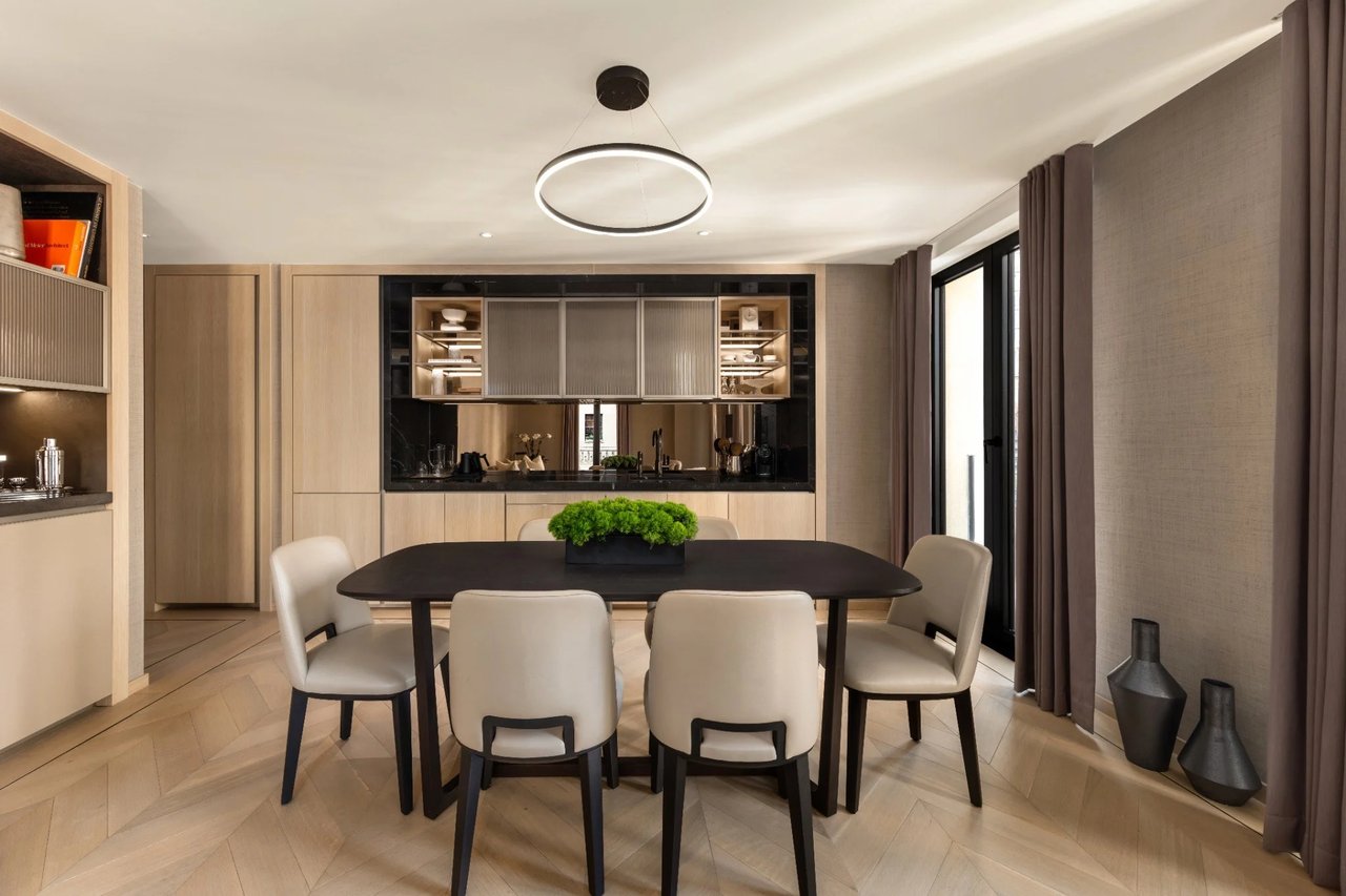 Dining room with a dark table, cream chairs, light wood cabinetry, and a built-in bar.