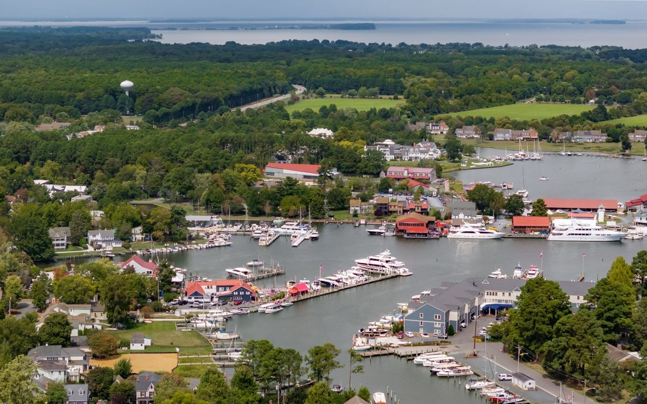 Aerial view of Saint Michaels harbor, with marina boats, waterfront buildings, and wooded shoreline.