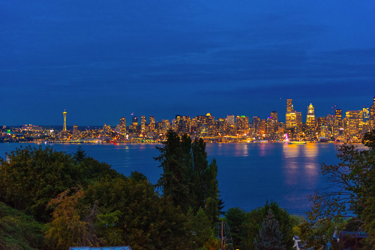 Seattle skyline across the water at night, with the illuminated Space Needle and city lights.