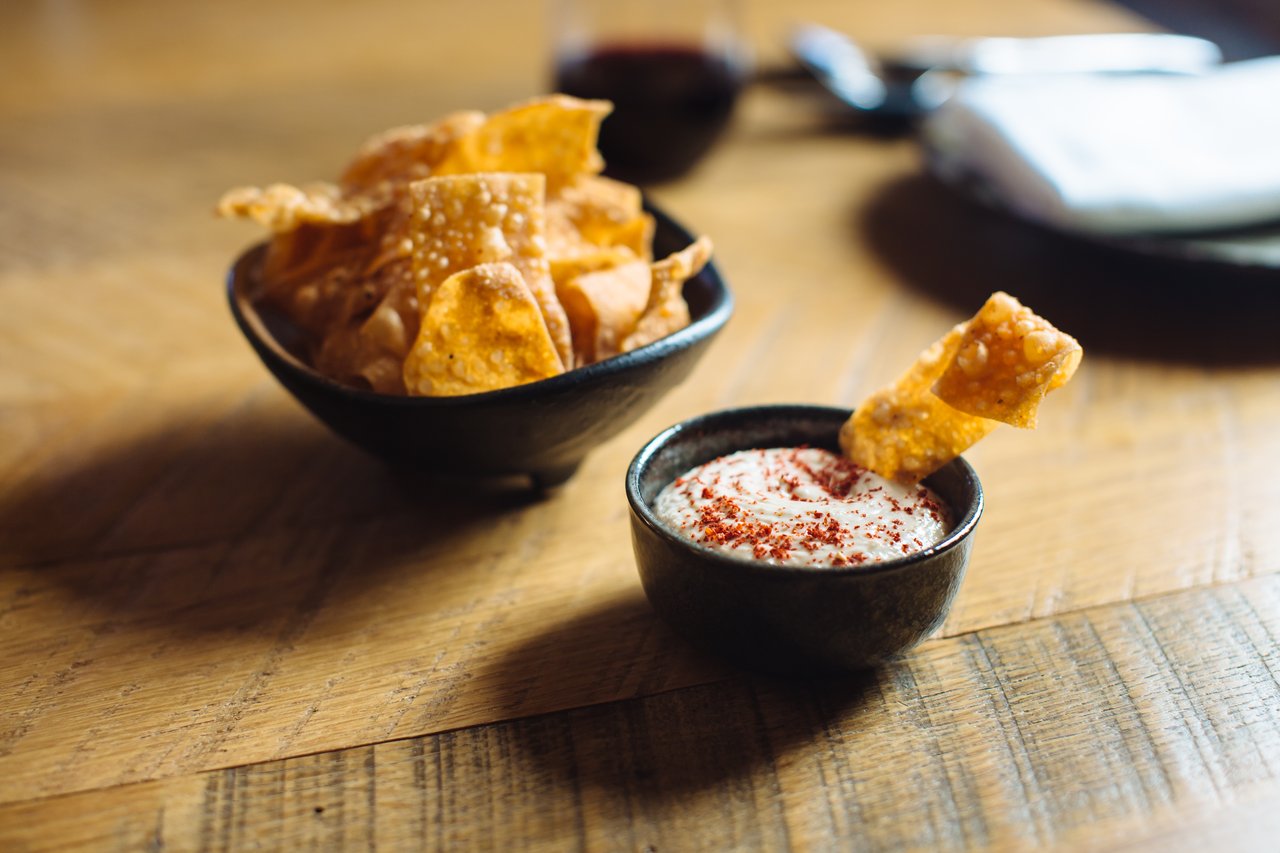 Tortilla chips and creamy dip on a wooden table.