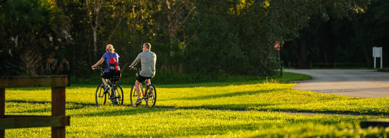 Couple biking on a nature trail at Tree Tops Park near Parkland, Florida.