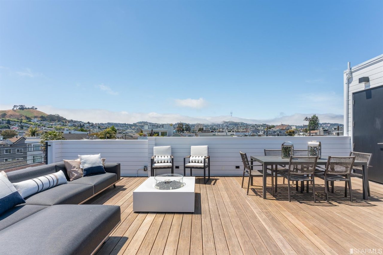 Rooftop deck with lounge seating, dining table, and panoramic views