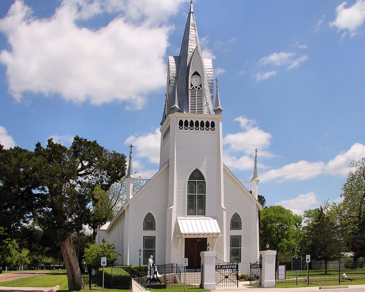 St. Joseph’s Church with a tall clock steeple and fenced entrance.