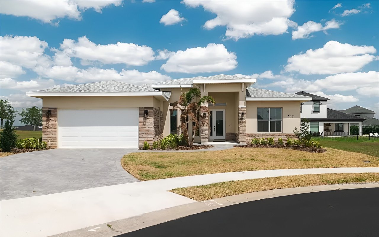 Modern single-story home with stone accents, a palm by the entry, and a curved driveway.