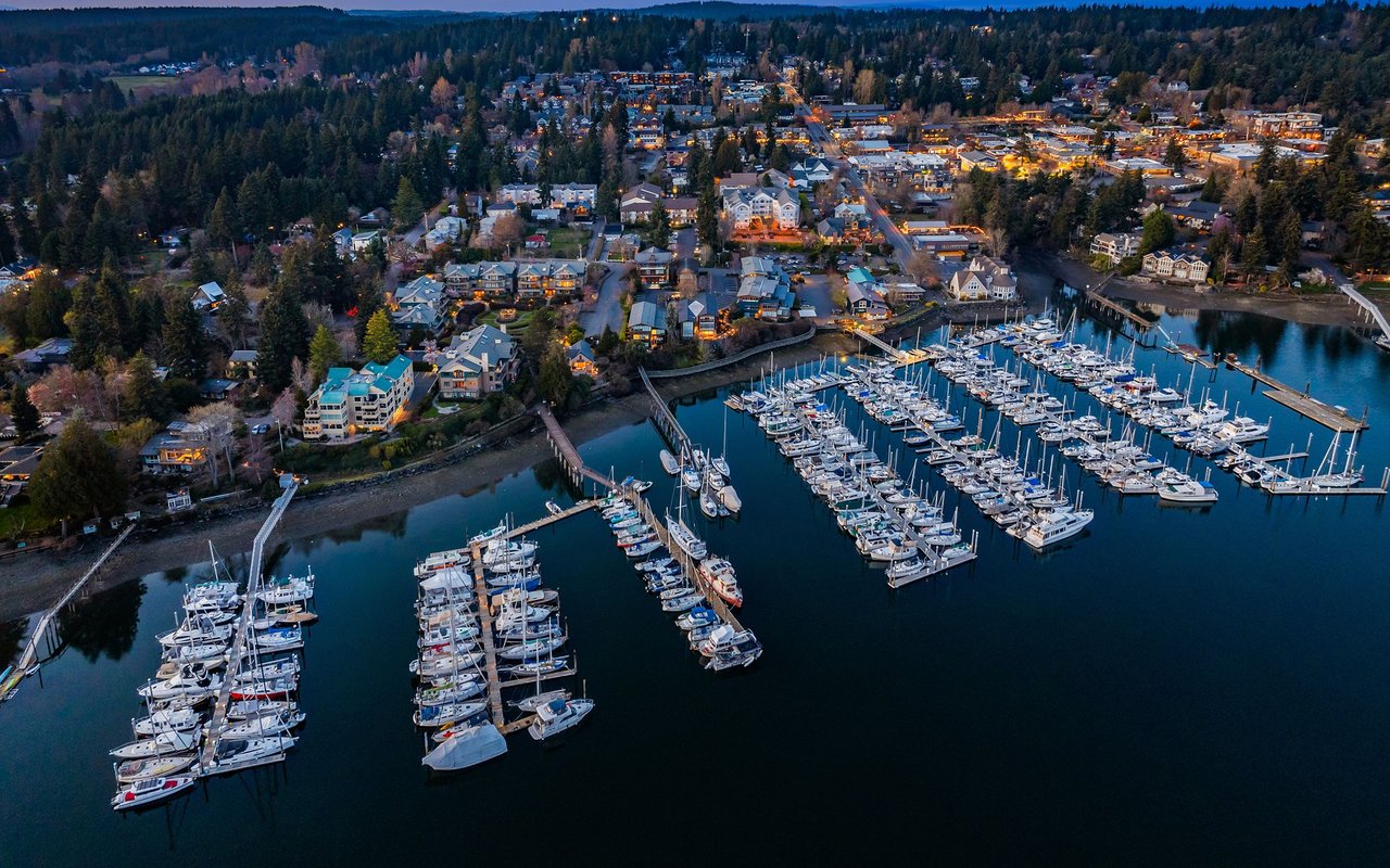 Eagle Harbor Marina at dusk, with boat-filled docks below the illuminated waterfront town.