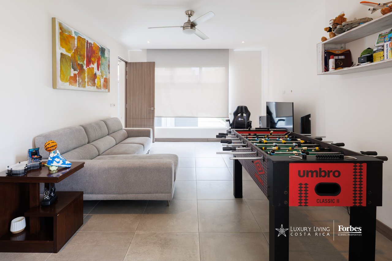 Furnished living room with a gray sectional sofa and a foosball table.