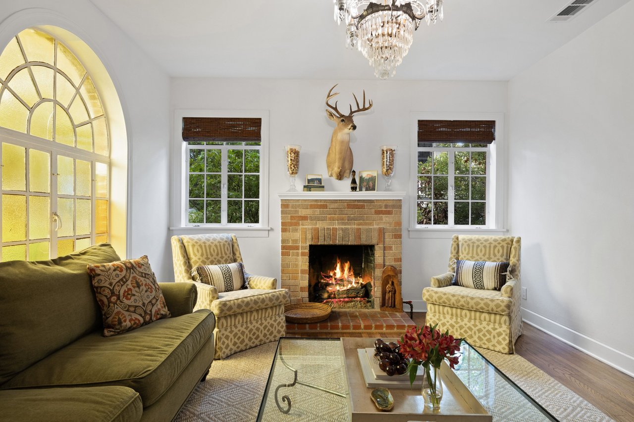 Living room with a brick fireplace, mounted deer head, and large arched window.
