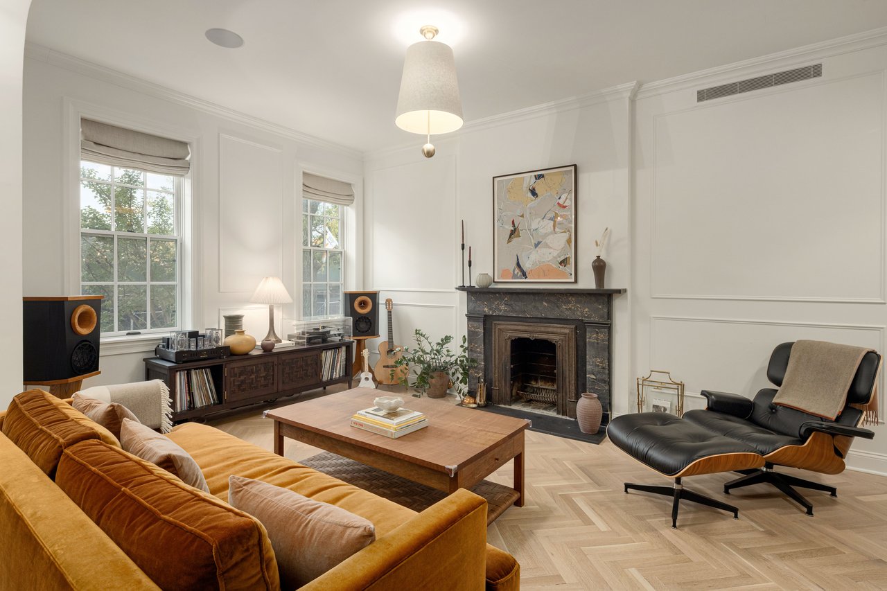 Living room featuring a rust velvet sofa, black Eames chair, and marble fireplace.