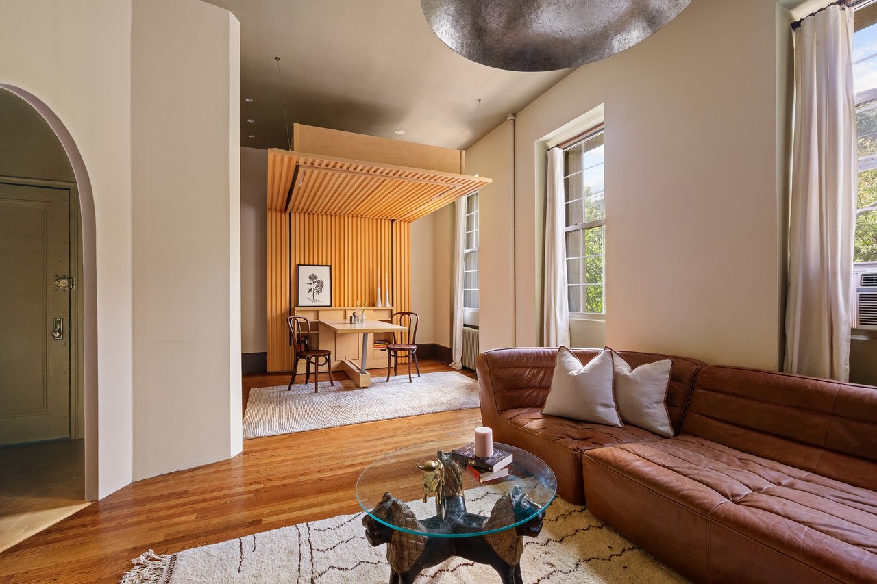 Living room with a brown leather sectional and a wood-slat canopy over the dining nook.