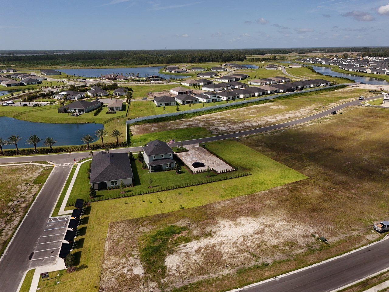 Aerial view of homes and ponds in a subdivision, with roads and undeveloped lots.