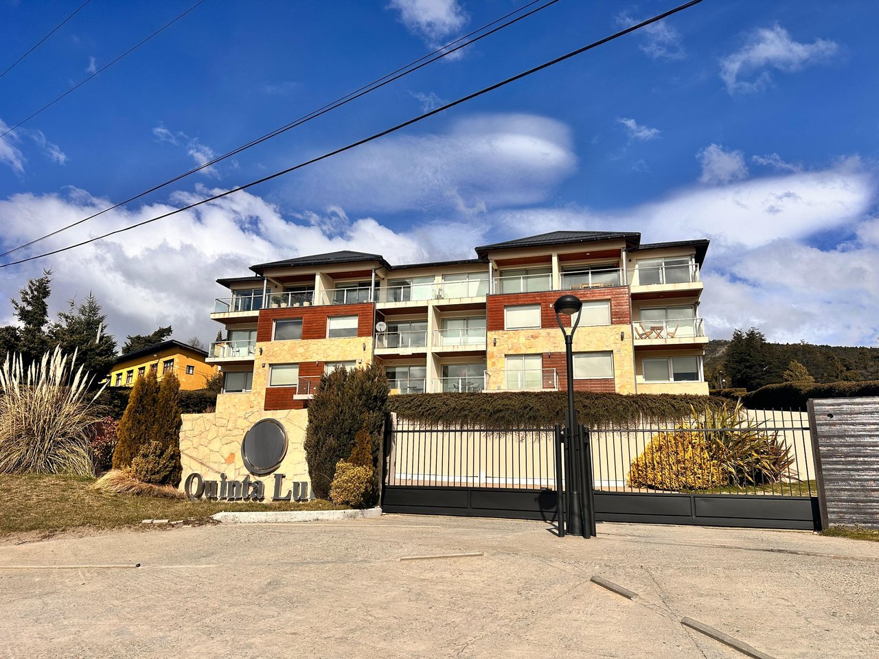 Multi-story residence with stone and wood facade, glass balconies, and a gated entrance marked Quinta Luna.