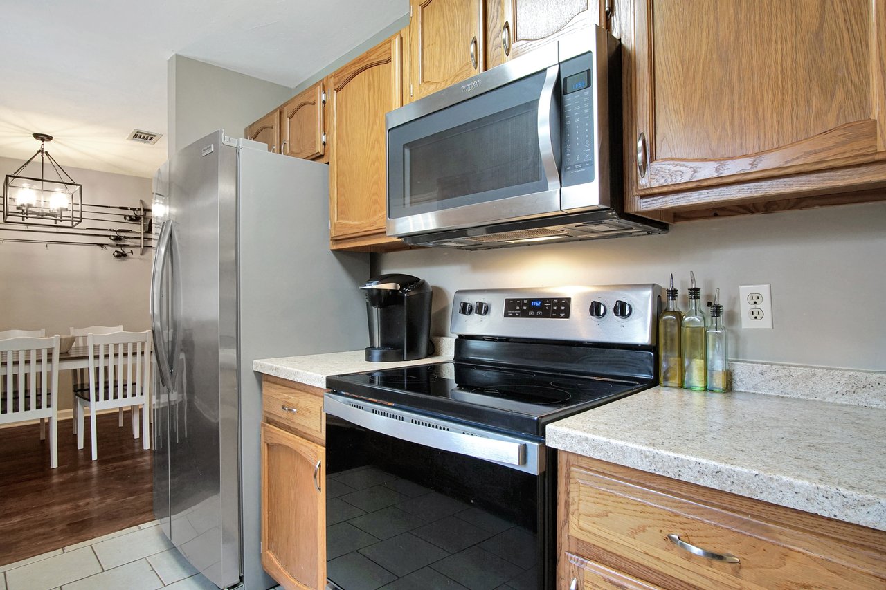 A modern kitchen featuring a stove, refrigerator, and microwave, showcasing a functional and organized cooking space.