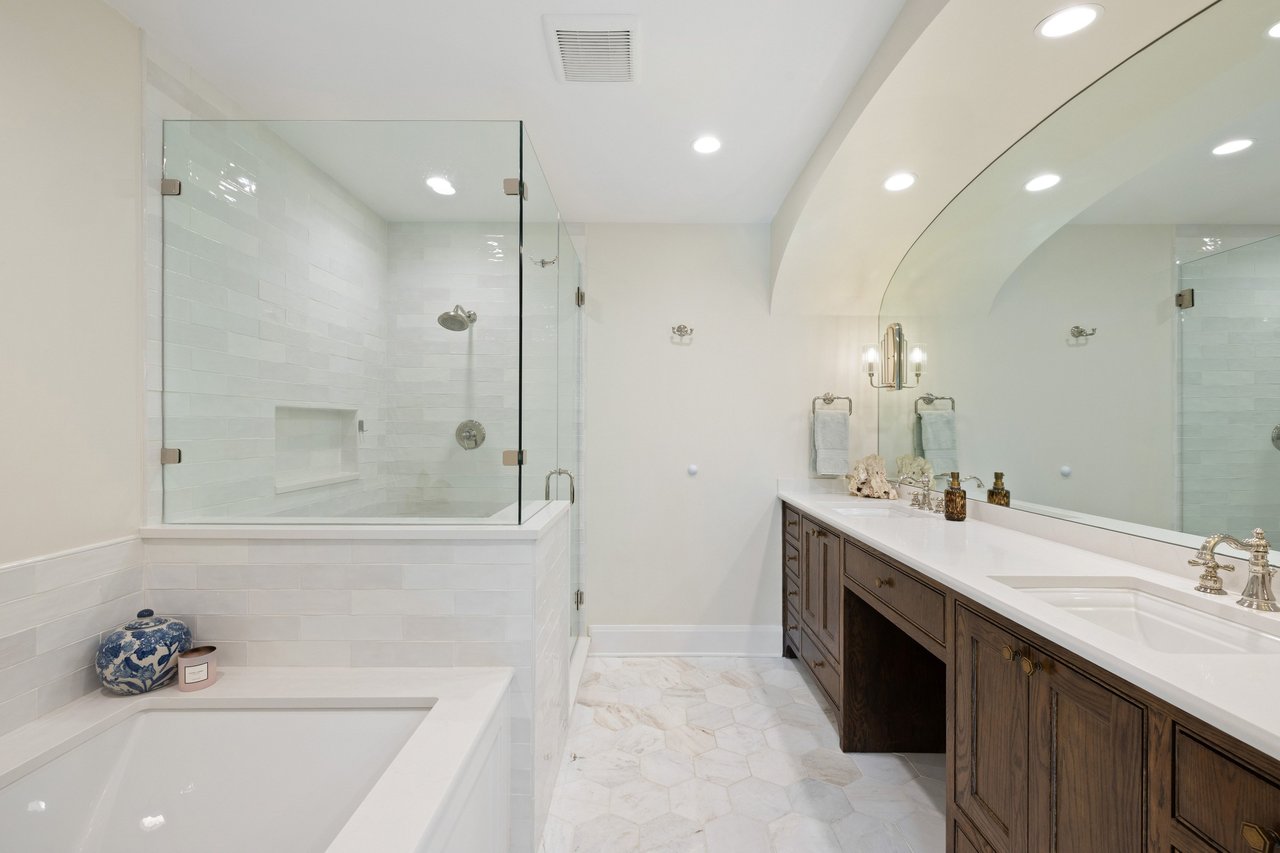 Bathroom with a soaking tub, glass-enclosed shower, and long dark wood vanity.