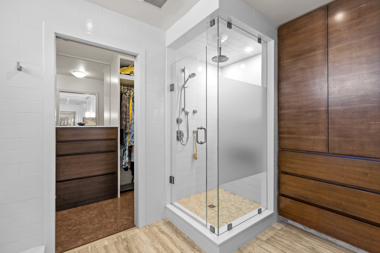Modern bathroom with a glass-enclosed shower, white tile, and dark wood cabinetry.