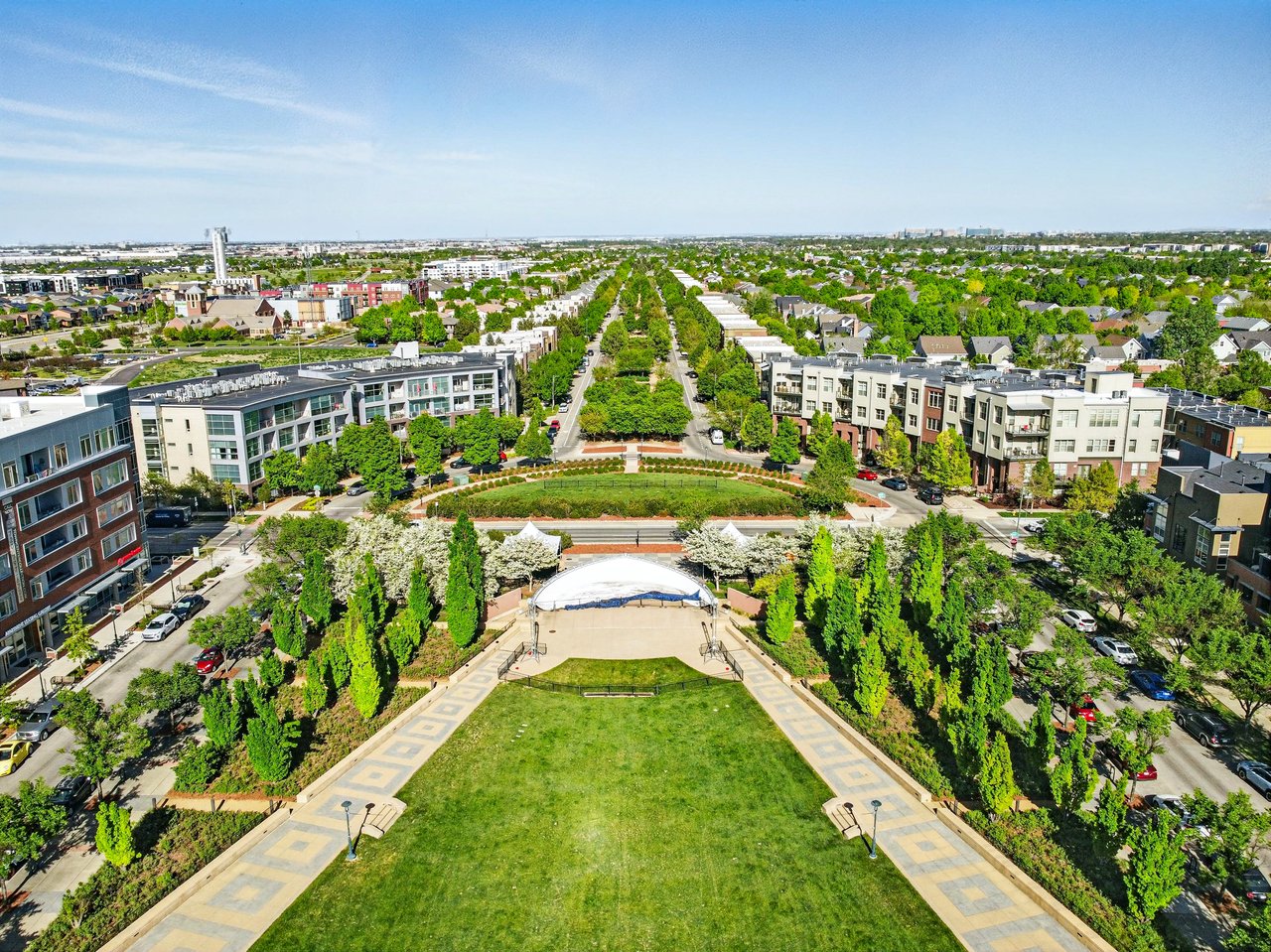 Aerial view of an urban neighborhood with tree-lined streets, residential buildings, and a central park area in Colorado.