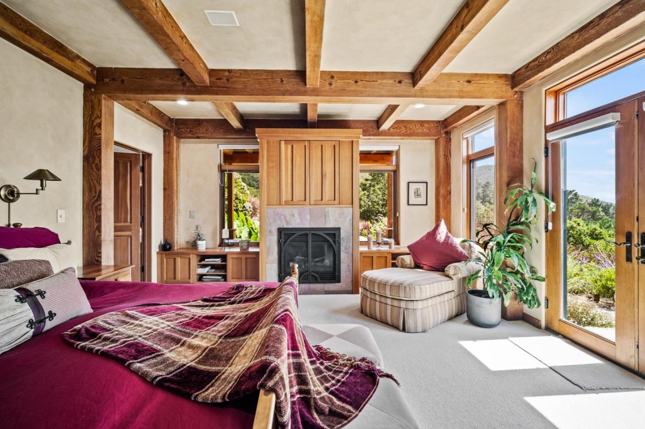 Primary bedroom with fireplace and balcony in $5.5M Carmel Highlands timber home