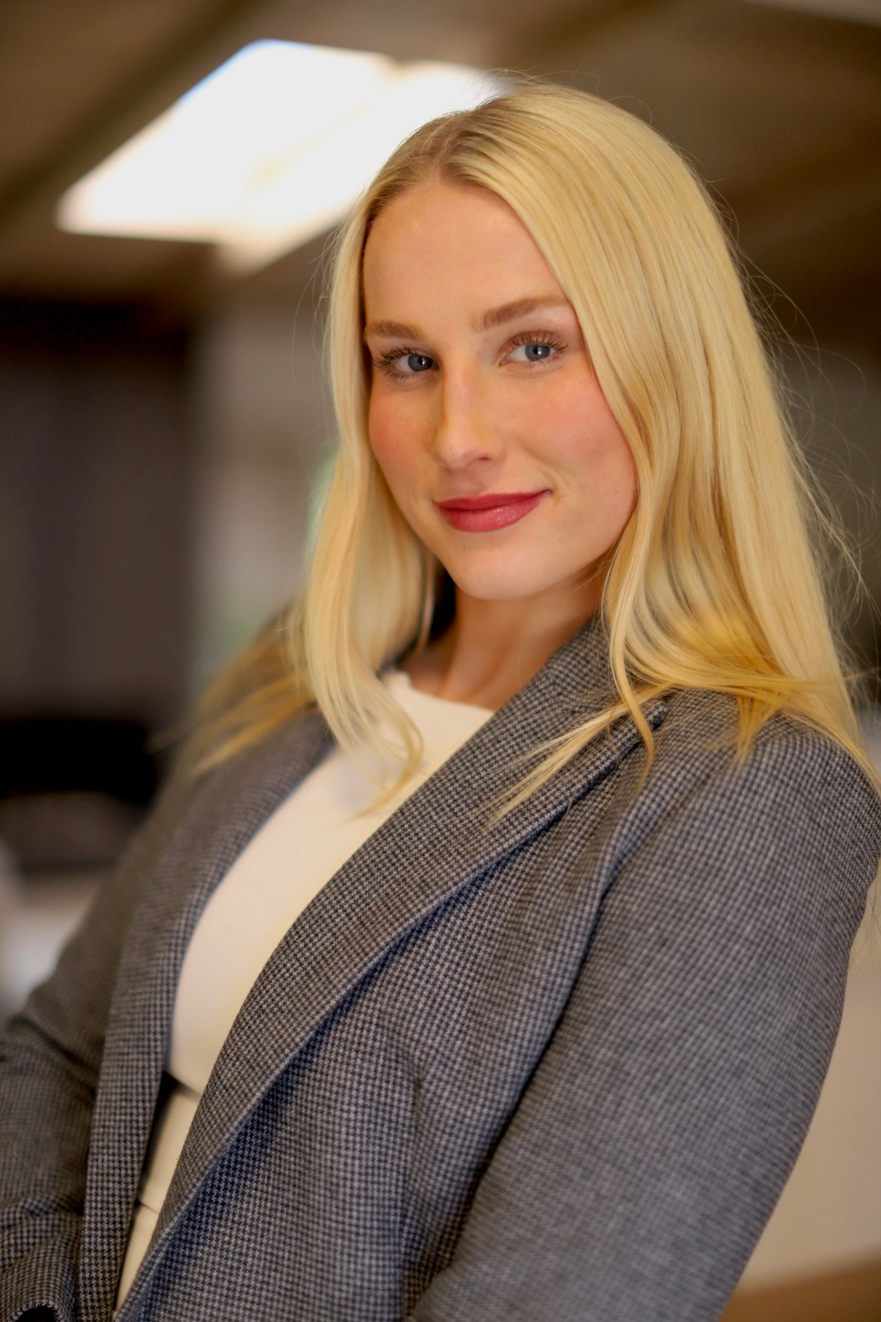 Erica Martinsen in a gray checked blazer, with long blonde hair.