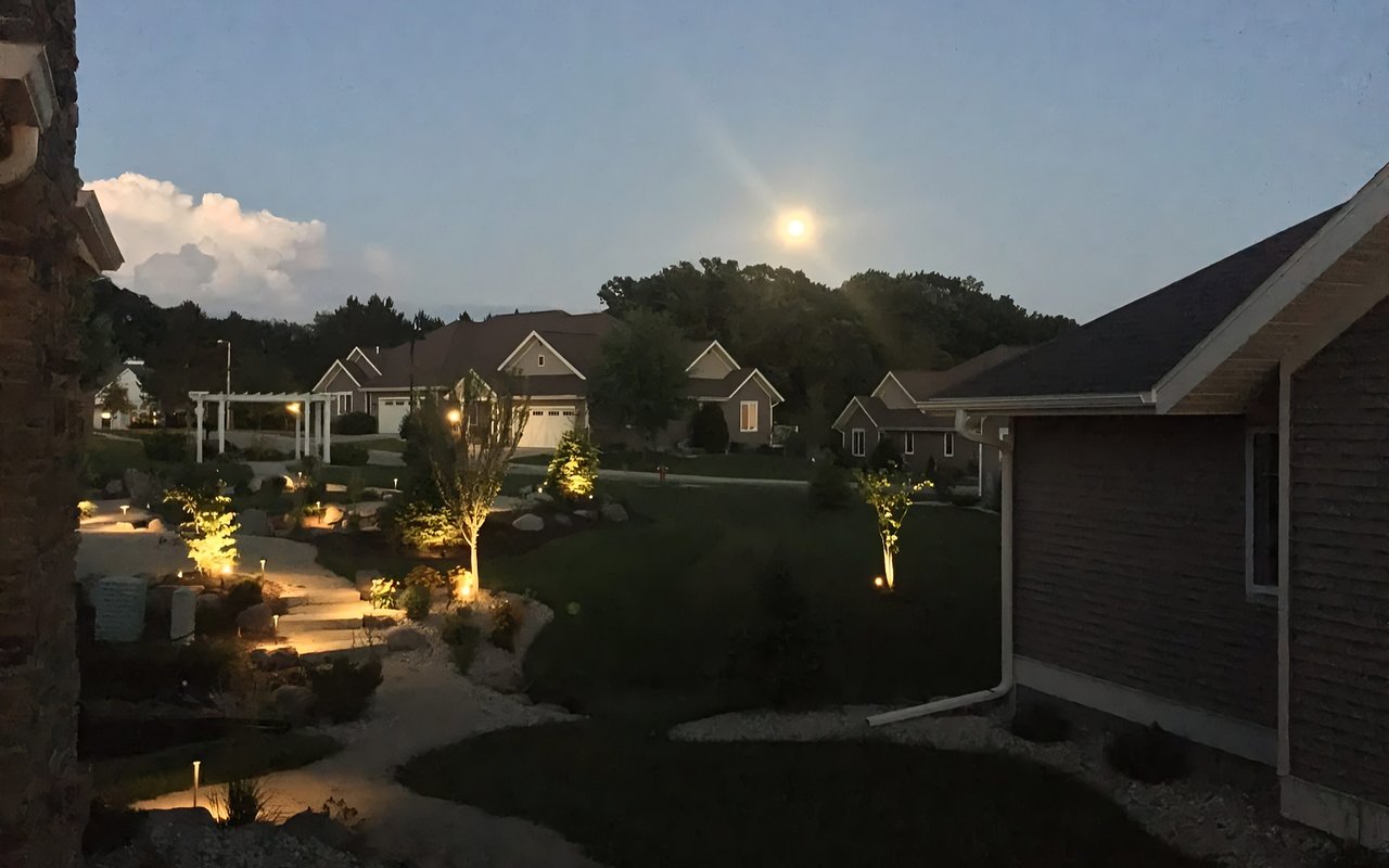 Landscaped neighborhood at dusk with a winding stone path and illuminated trees.