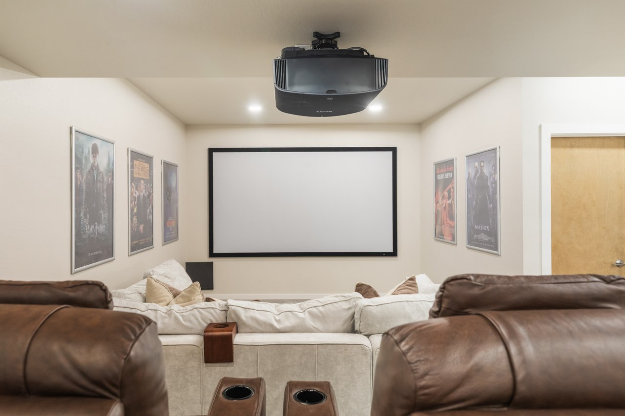 Home theater with a large projection screen, ceiling-mounted projector, and leather recliners