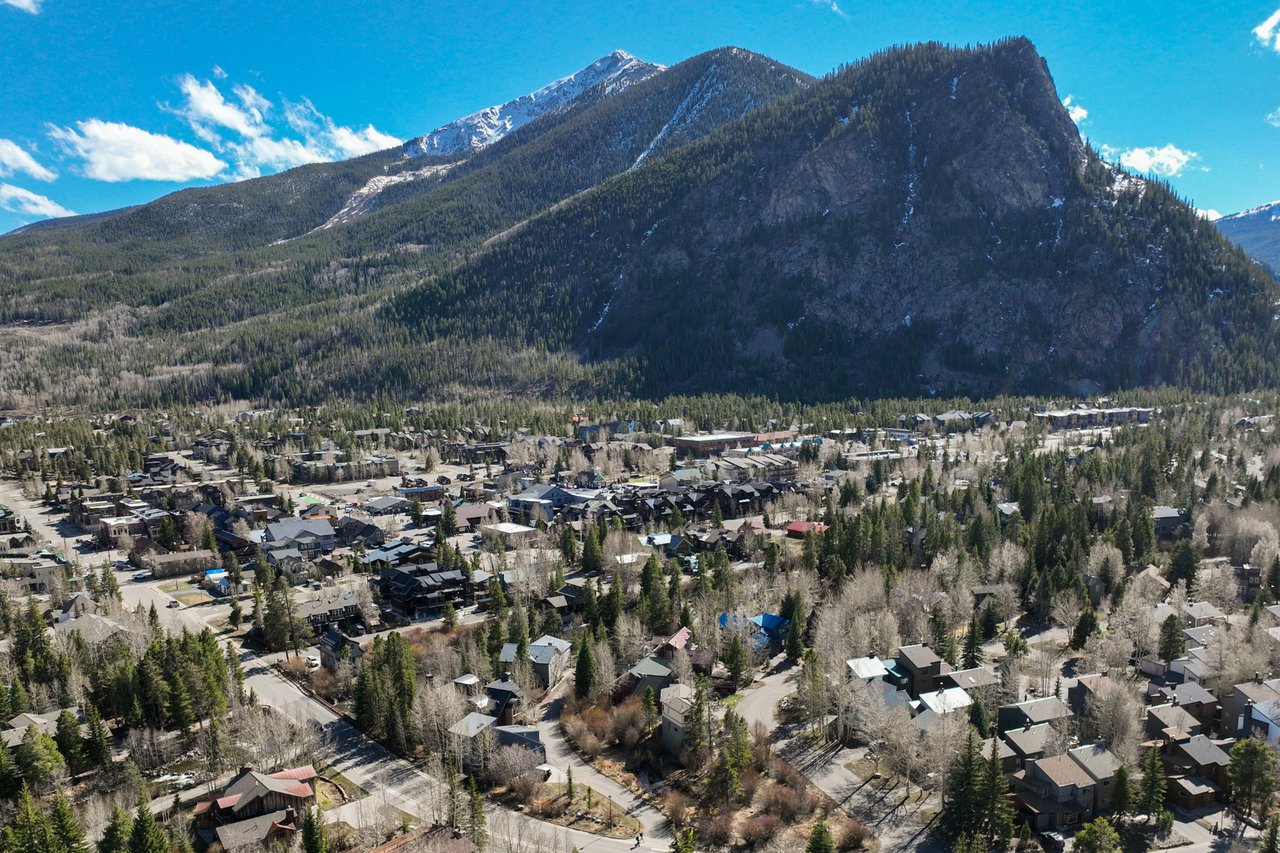 Aerial view of Frisco beneath a forested mountain with patches of snow.