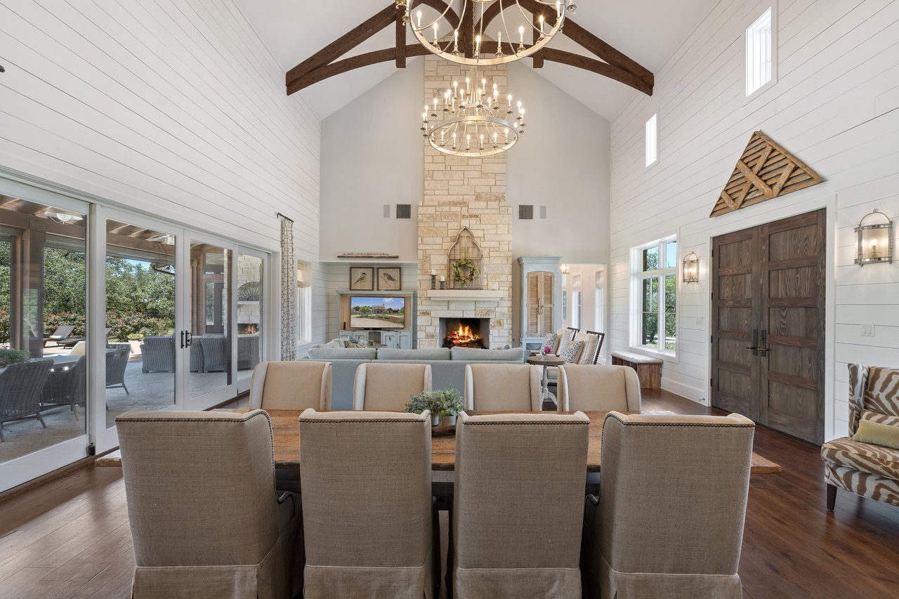 Great room at 335 Winning Colors showing the vaulted beamed ceiling, chandelier, and wood entry door with iron lantern sconces.