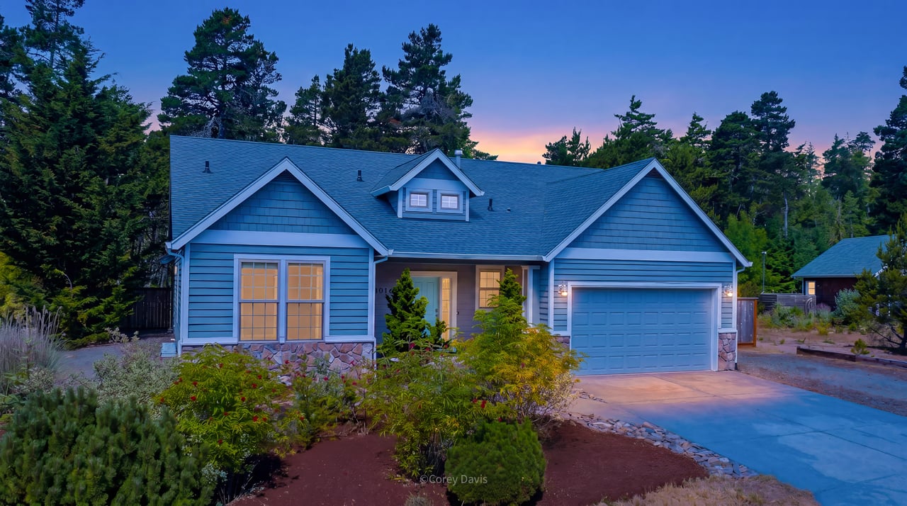 Sold single-level home at 10140 Pine Ridge Dr in Manzanita, Oregon, listed by Meadow Davis of Home + Sea Realty, with forest views, covered patio, fire pit, and three-car garage.