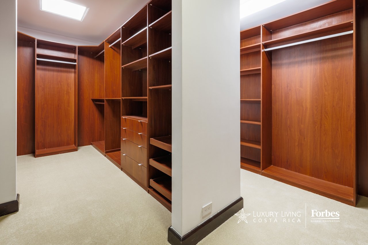 Walk-in closet with reddish-brown built-in wardrobes, open shelving, drawers, and a skylight.