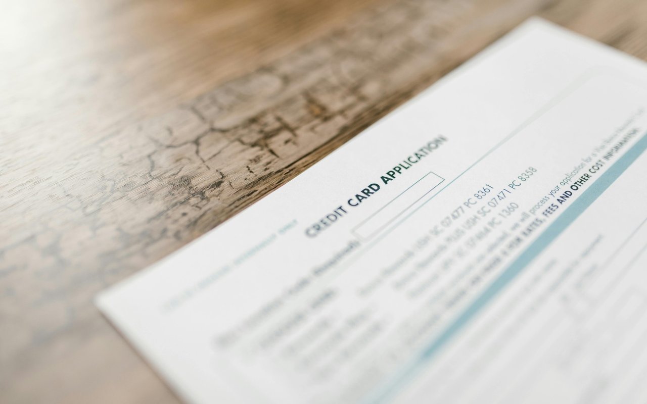 Credit card application form on a worn wooden tabletop.