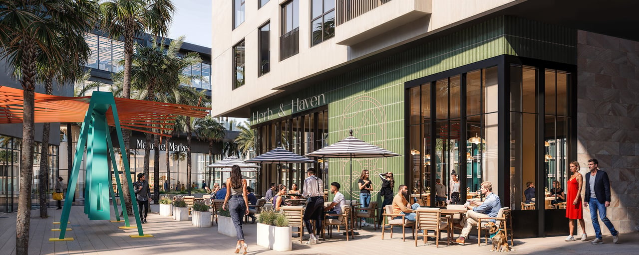Cello Tower retail plaza with Herb & Haven storefront, outdoor café seating, palm trees, and teal sculpture.