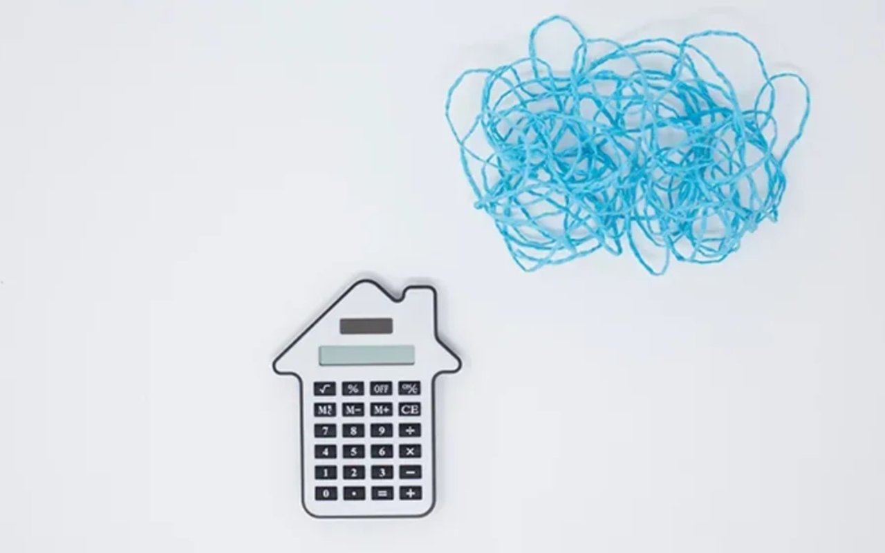 House-shaped calculator beneath a tangled blue scribble, illustrating uncertainty about home equity.