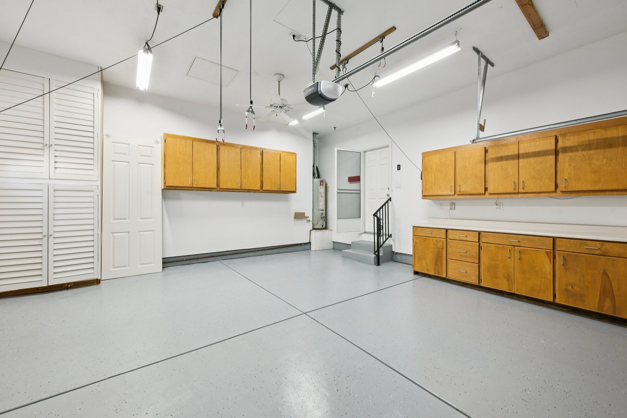 Empty garage with honey-colored storage cabinets and a light gray speckled floor.