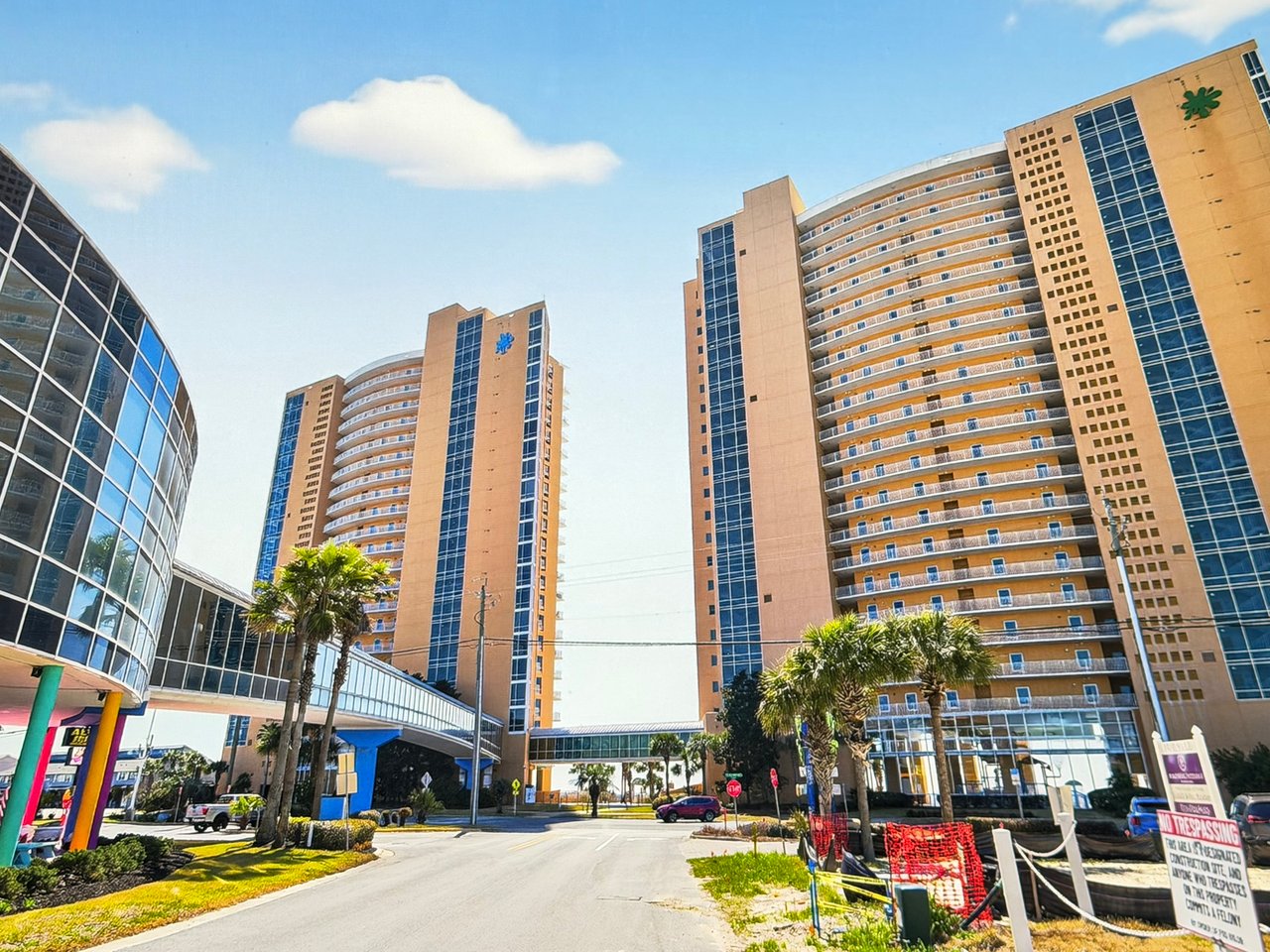 Street-level view of the luxury condo towers and enclosed pedestrian skybridge at Splash Beach Resort in Panama City Beach.