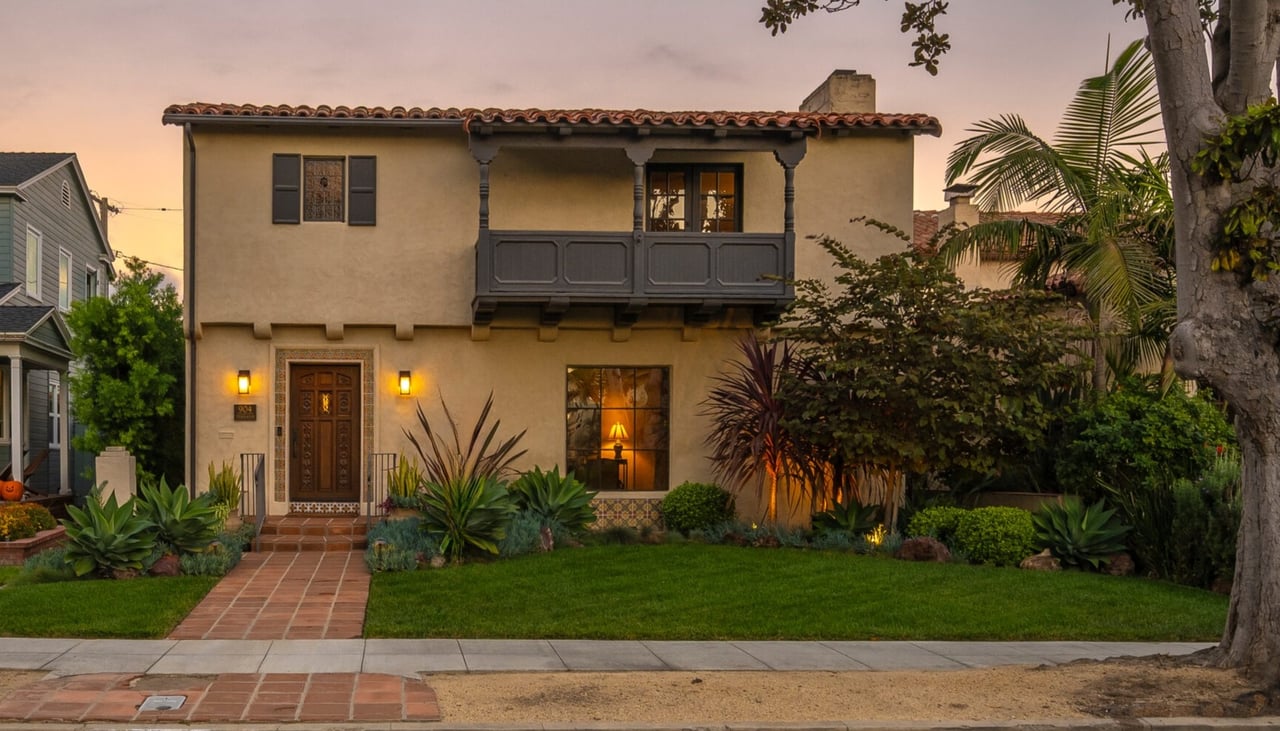 Spanish-style home in Alamitos Heights at twilight with lush landscaping and warm exterior lighting in Long Beach California