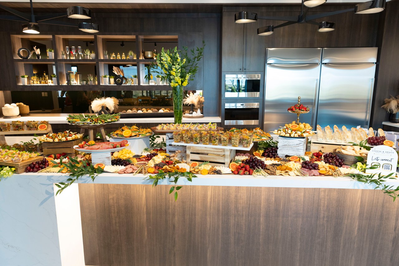 A lavish buffet of charcuterie, cheeses, fruit, and appetizers in a modern kitchen.