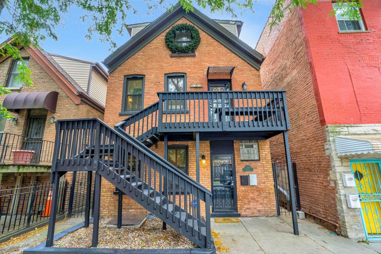 Orange-brick home with a raised dark deck and exterior staircase.