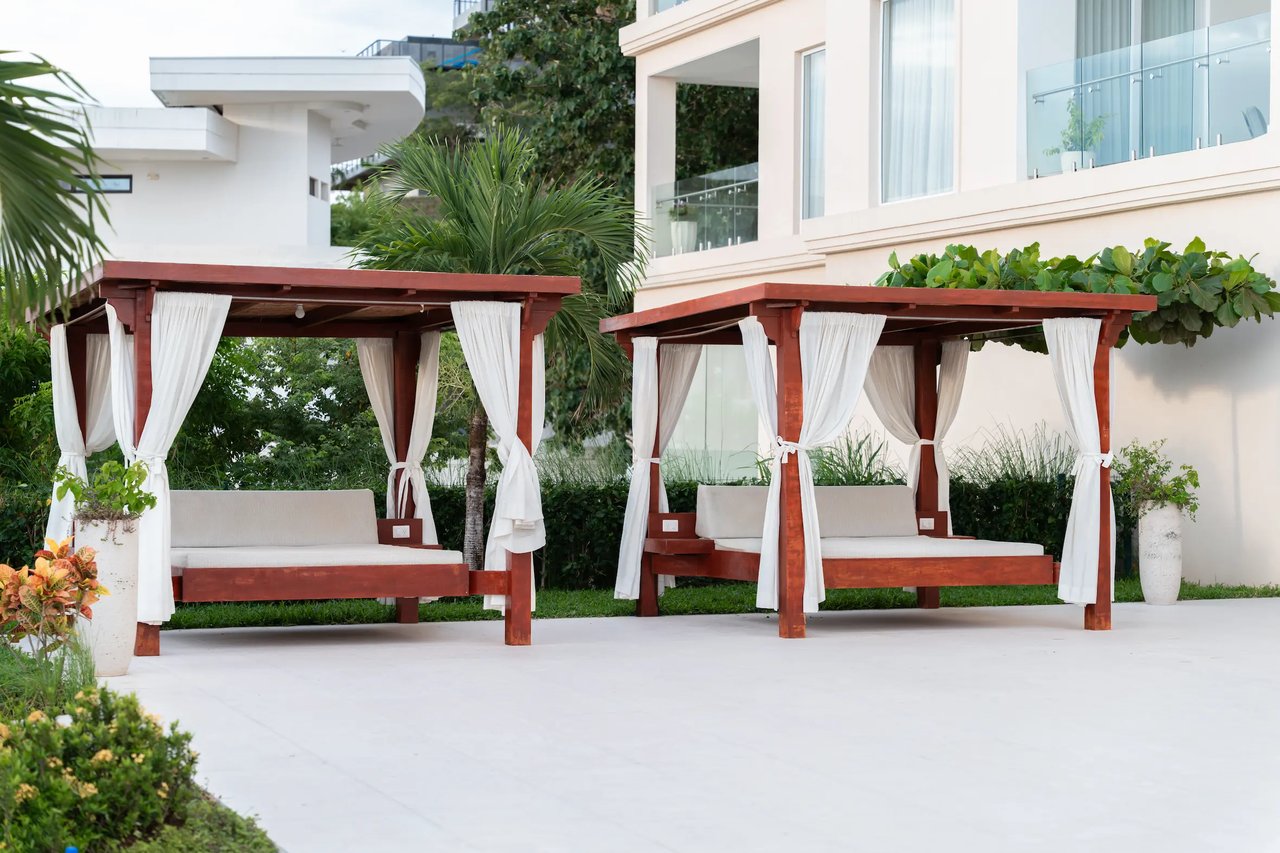 Condominium courtyard with curtained cabanas, cushioned daybeds, and tropical landscaping.