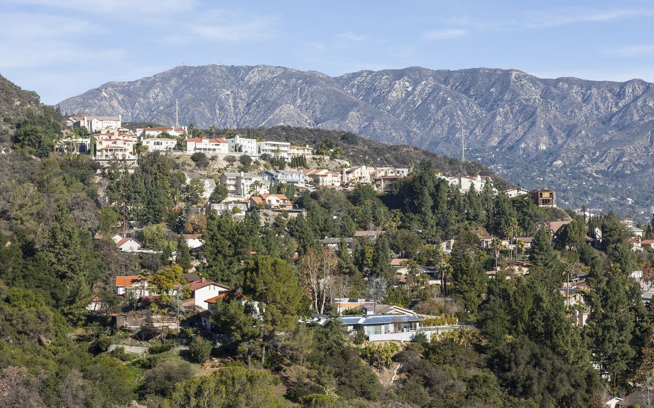 Hillside homes among trees with the San Gabriel Mountains behind them.